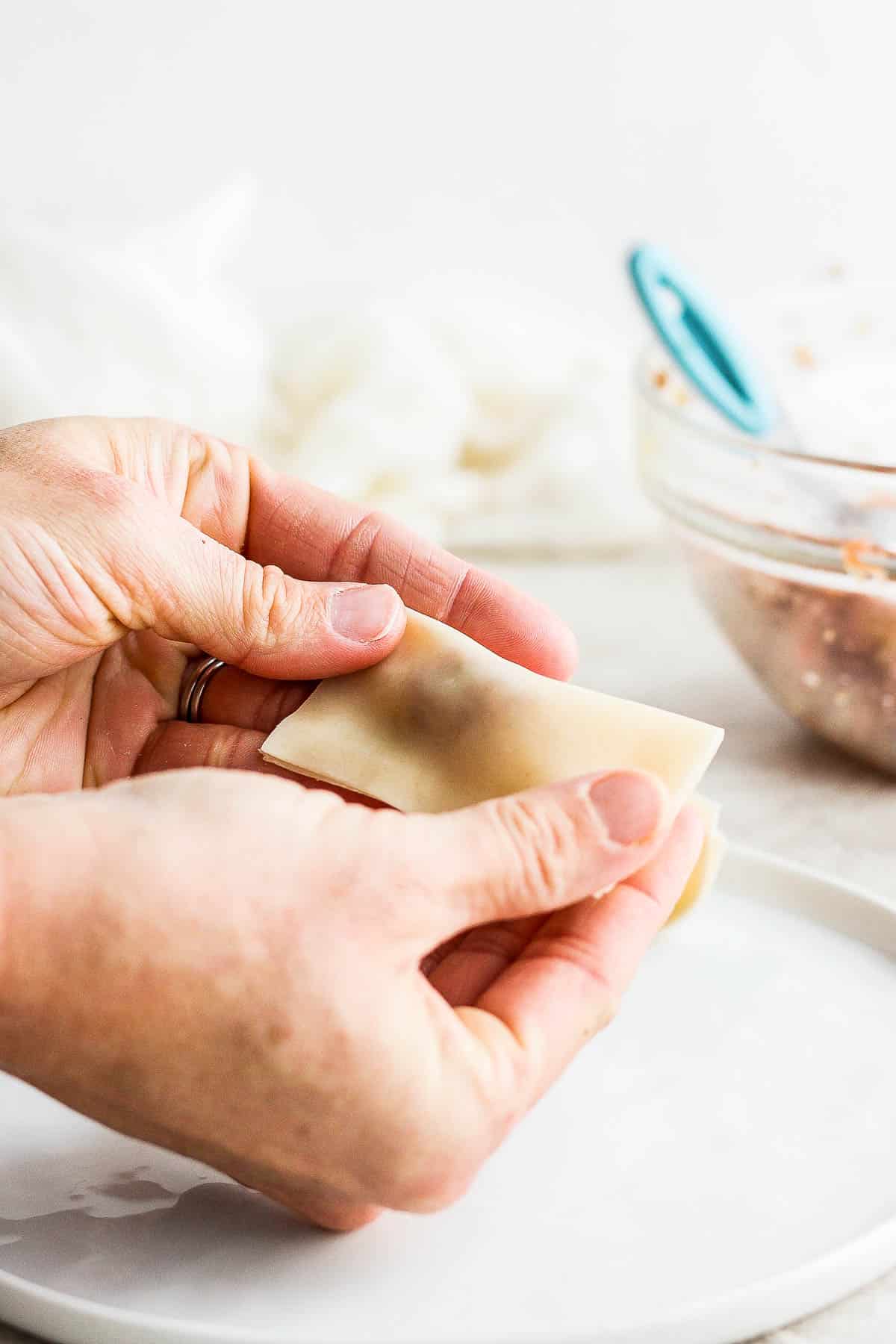 Someone pressing down the edges to seal in the pork filling. 