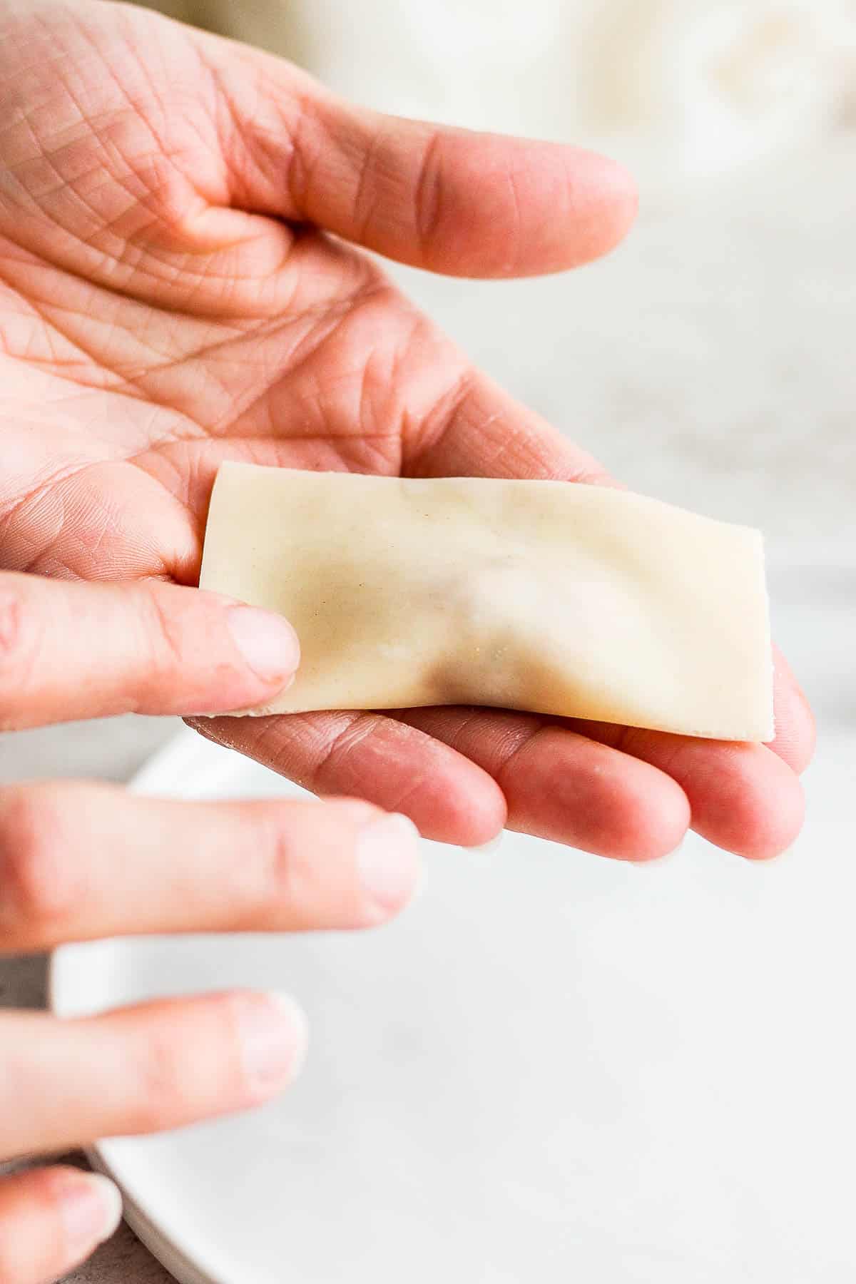 Someone wetting the corner of the folded-in-half pork wonton. 