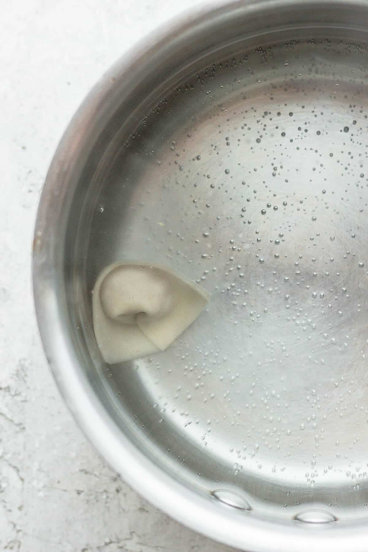 A pork wonton in a pot of hot water.
