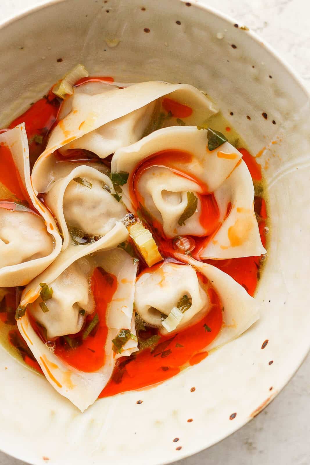 Bowl of spicy pork wontons with red chili broth.