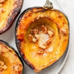 A halved, roasted acorn squash on a plate.