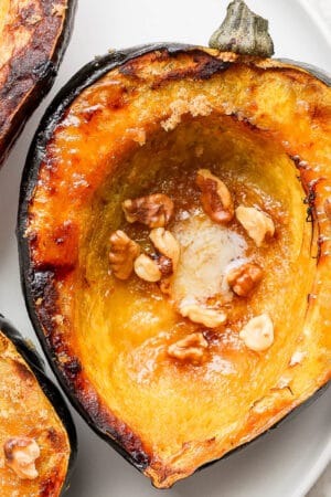 A halved, roasted acorn squash on a plate.