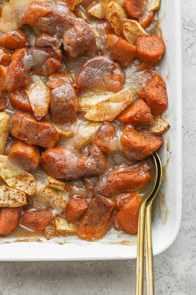 Casserole dish filled with apple yam bake and two spoons. 