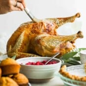 Someone basting a deep fried turkey on a platter.