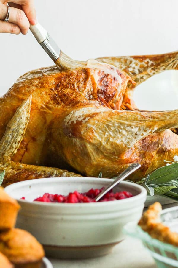 Someone basting a deep fried turkey on a platter.