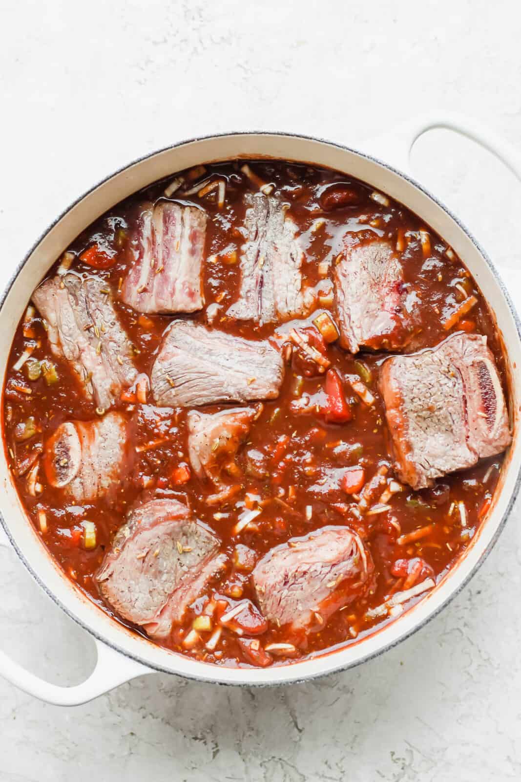 Seared short ribs back in the Dutch Oven along with the braising liquid.