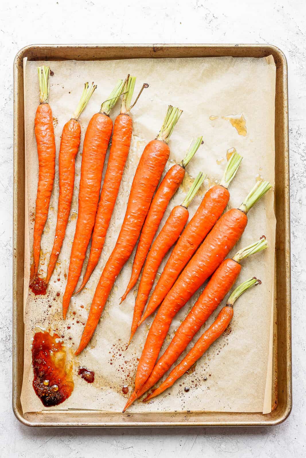 Whole roasted carrots on a baking sheet.