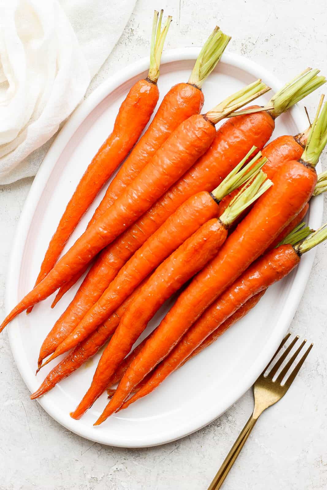 Whole roasted carrots on a small platter.