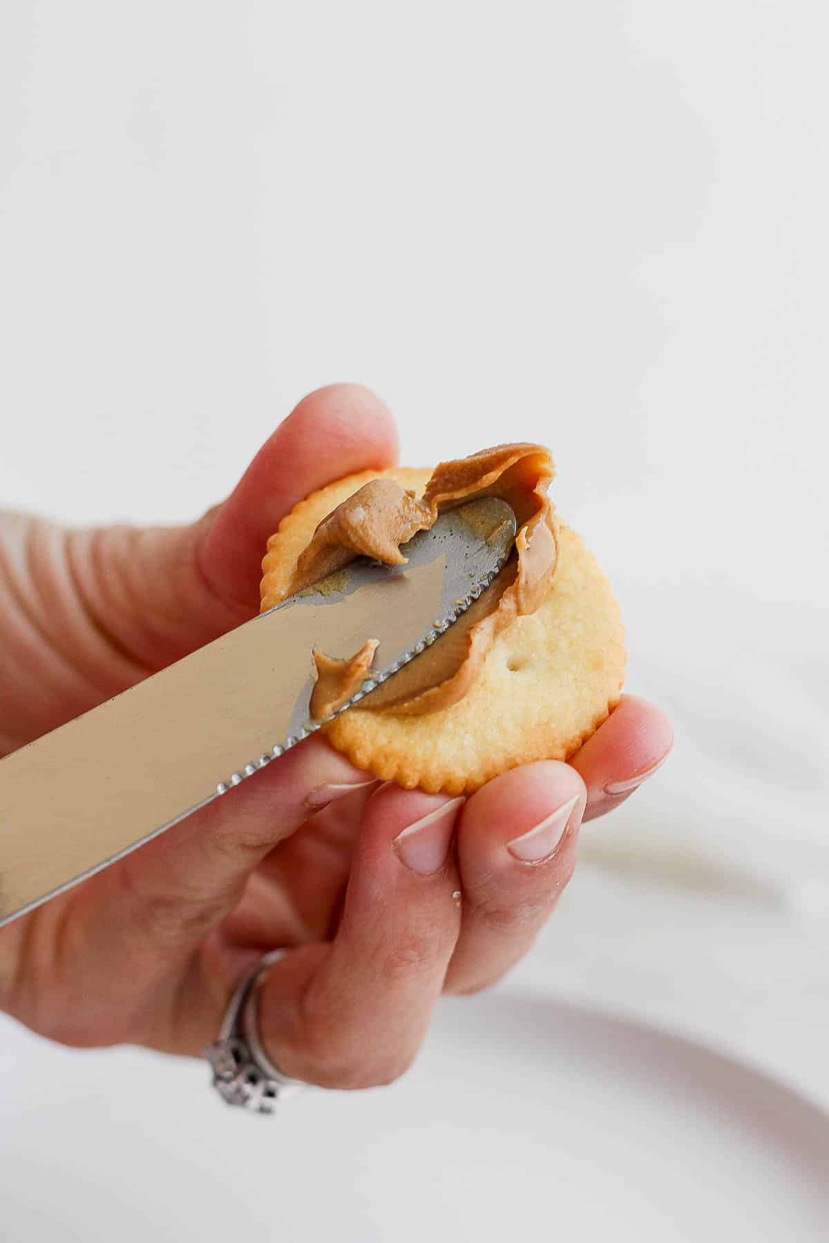 Someone spreading peanut butter on a Ritz cracker. 