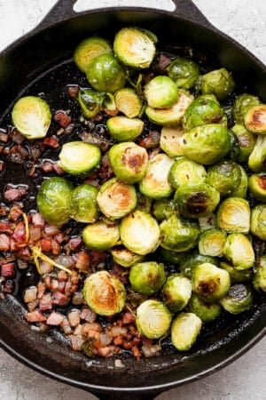 Cast iron skillet filled with roasted brussel sprouts and pancetta.