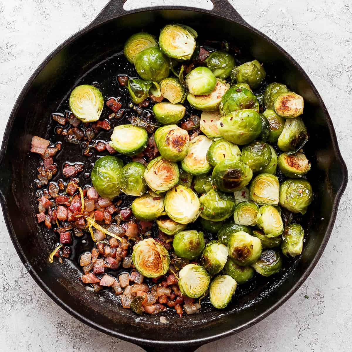 A cast iron skillet with roasted brussel sprouts and pancetta.
