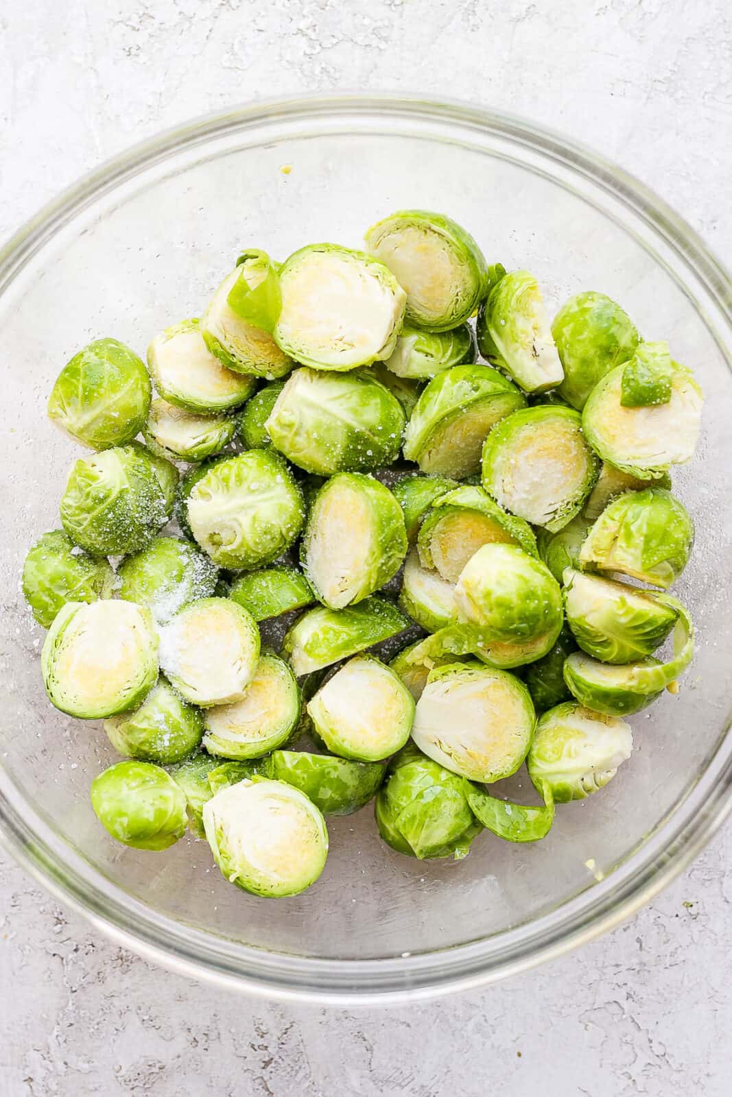 Bowl of halved brussel sprouts with olive oil and salt. 