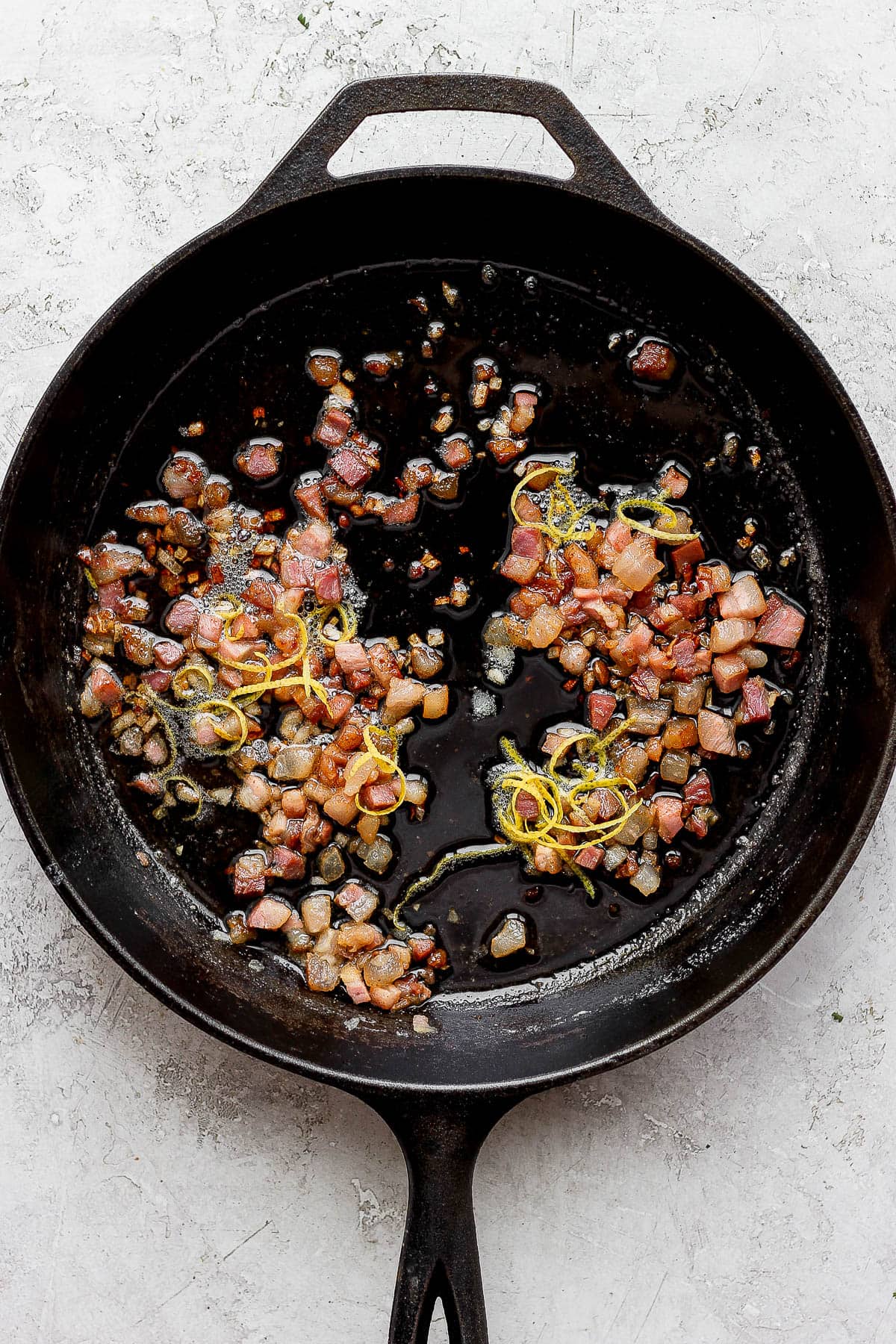 Cast iron skillet with shallots, pancetta and lemon zest inside.