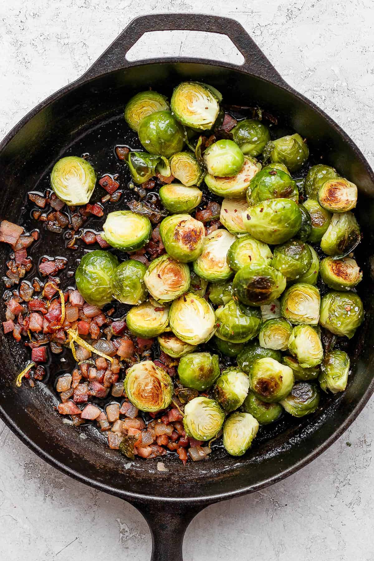 Cast iron skillet filled with roasted brussel sprouts, pancetta and lemon zest.