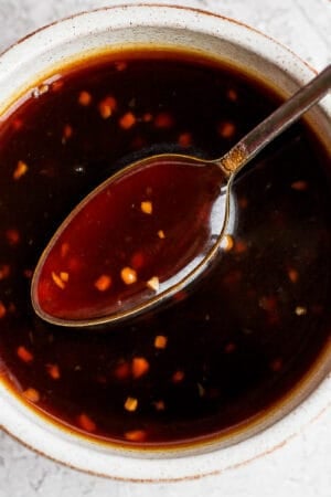 Bowl of homemade teriyaki sauce with a spoon lifting out of it.