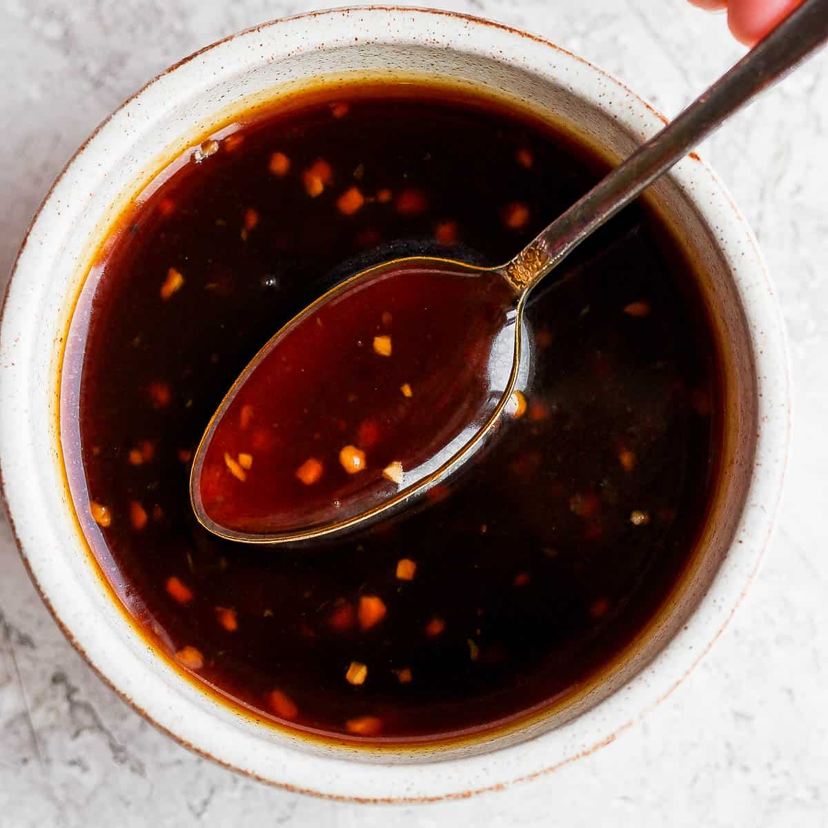 Bowl of homemade teriyaki sauce with a spoon lifting out of it.