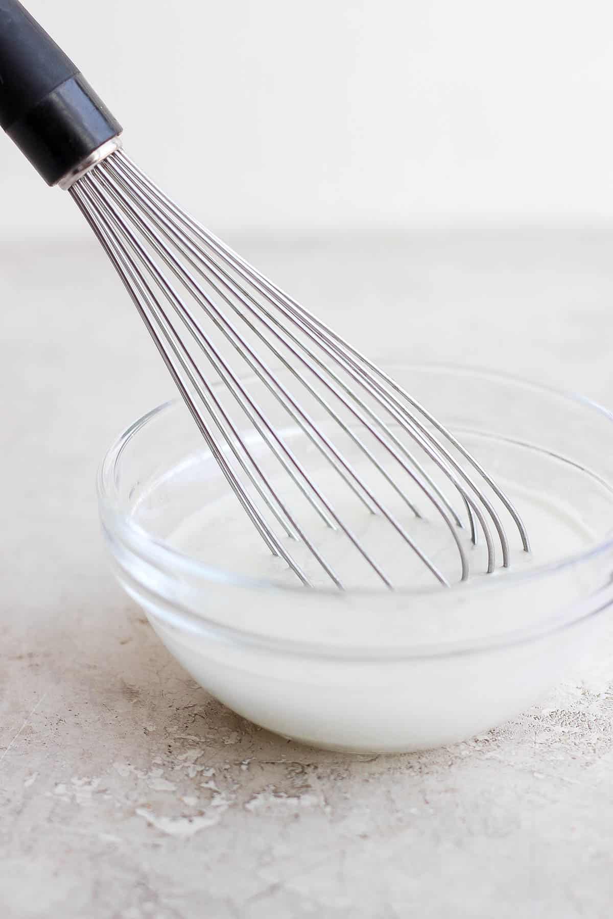 Someone whisking together a slurry in a small bowl.