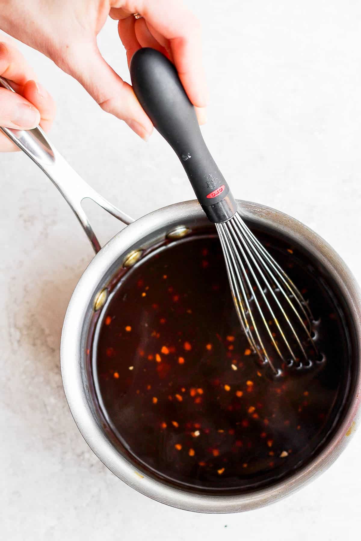 Teriyaki sauce in a small saucepan with a whisk.
