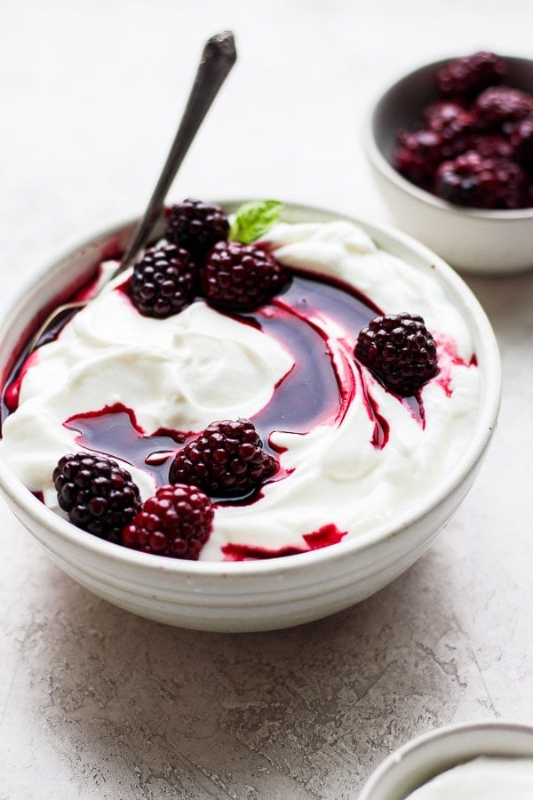 Blackberry compote in a bowl with yogurt and a spoon.