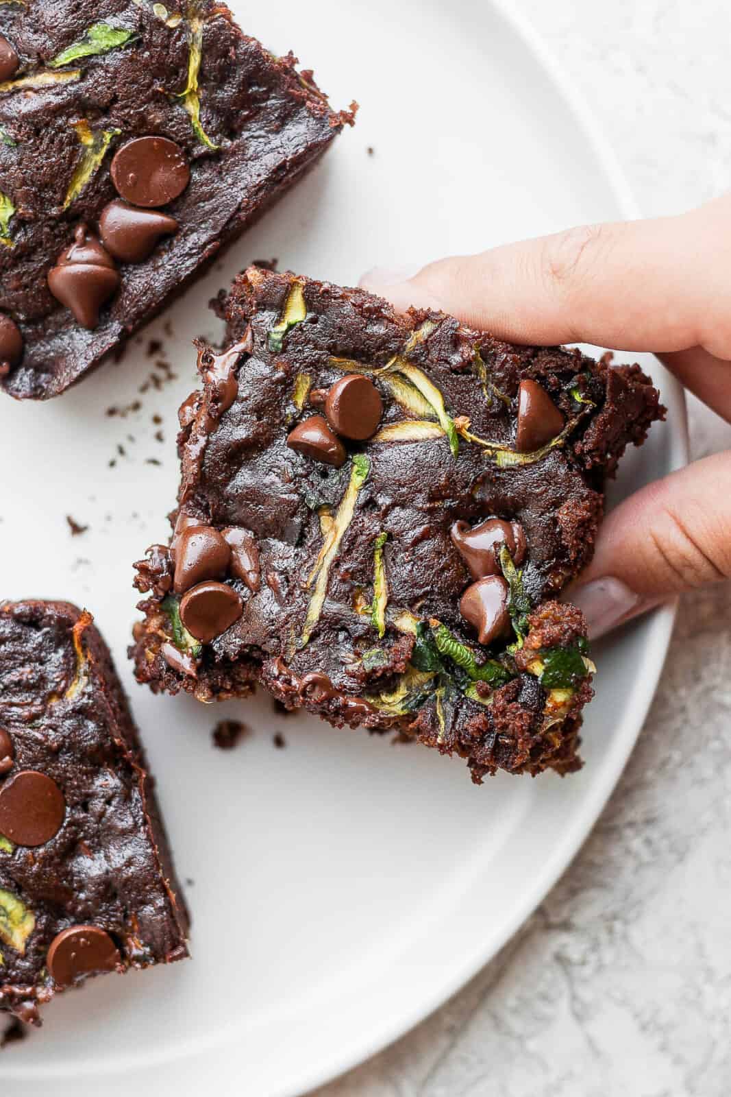 Three zucchini brownies on a plate.