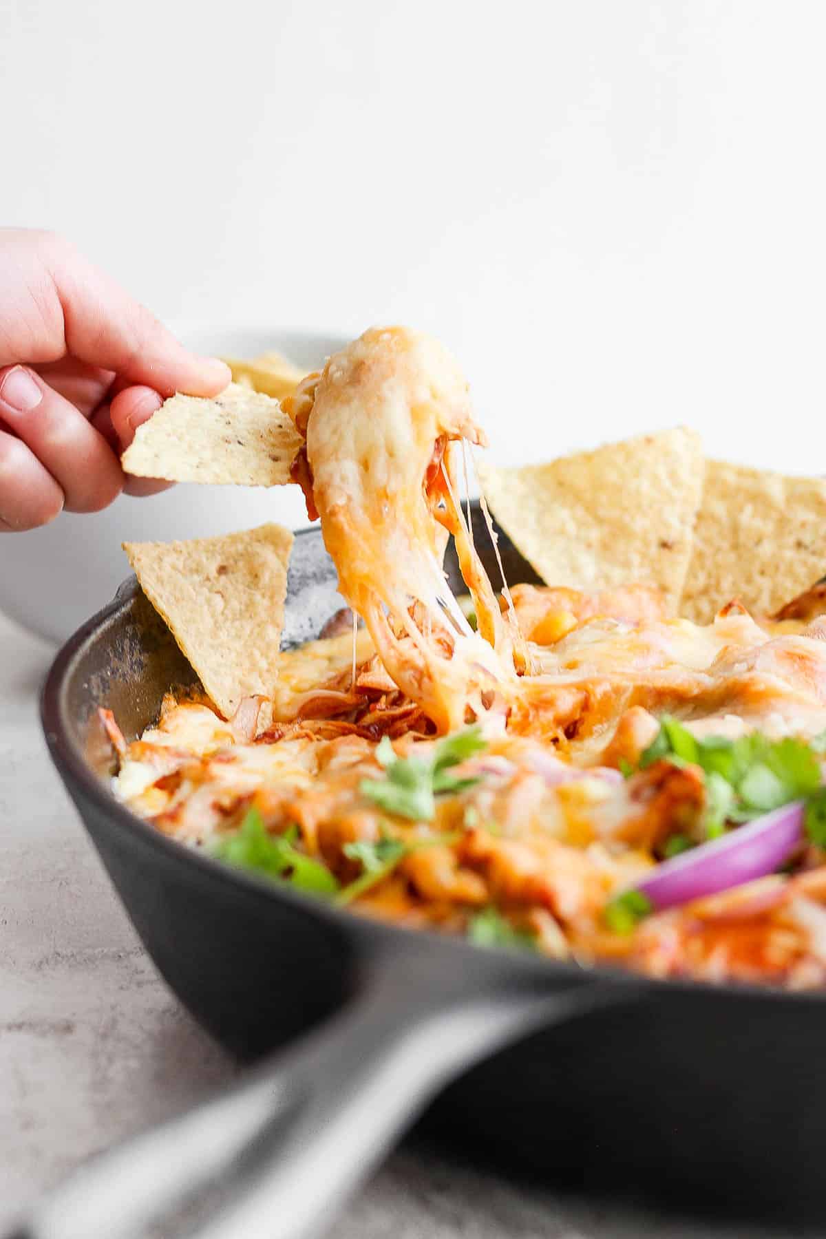 Someone pulled scooping up some bbq chicken dip with a chip.