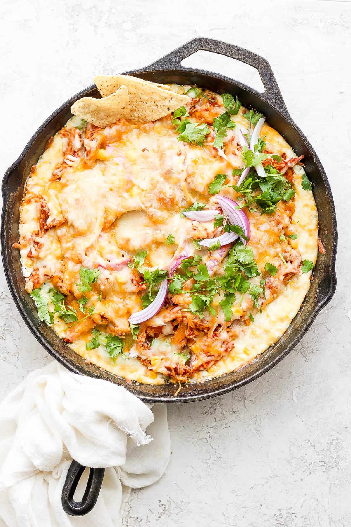 BBQ Chicken Dip in a cast iron skillet with a few chips sticking out. 
