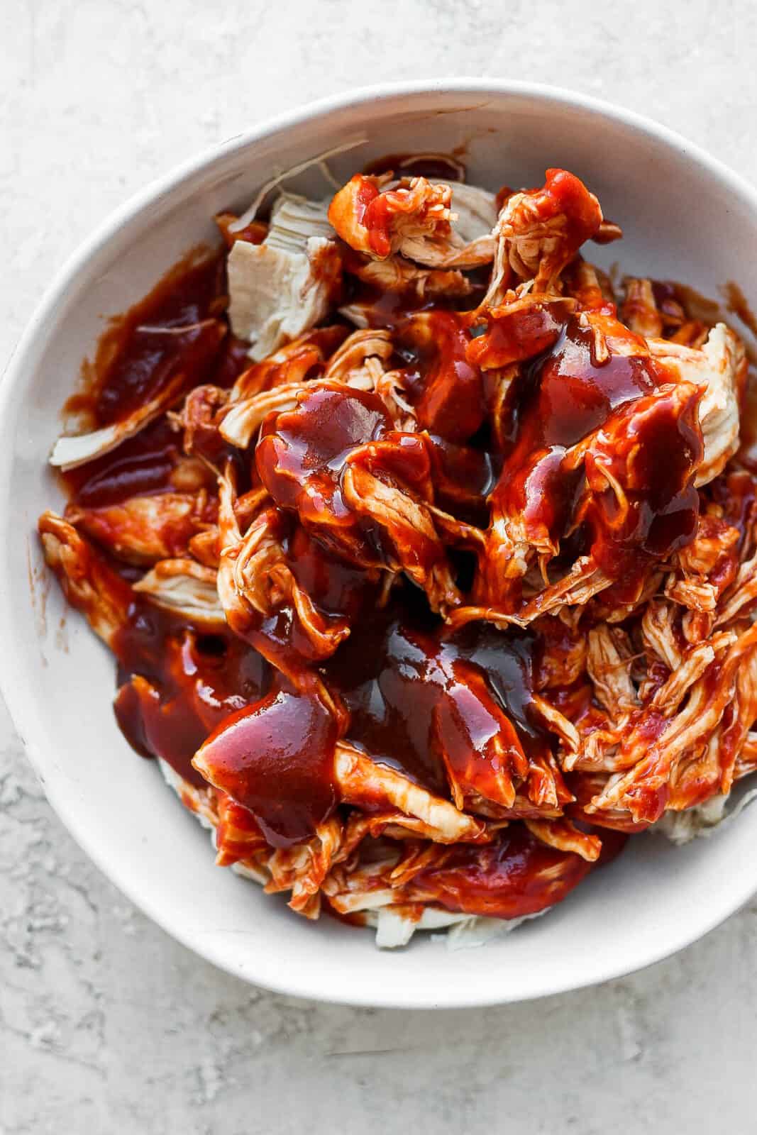 Shredded chicken topped with bbq sauce in a bowl.