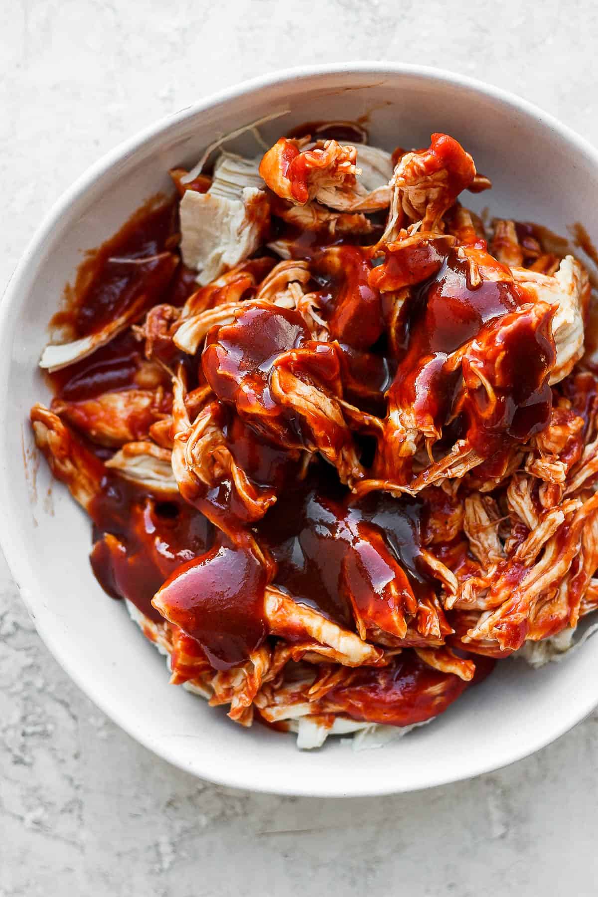 Shredded chicken topped with bbq sauce in a bowl.