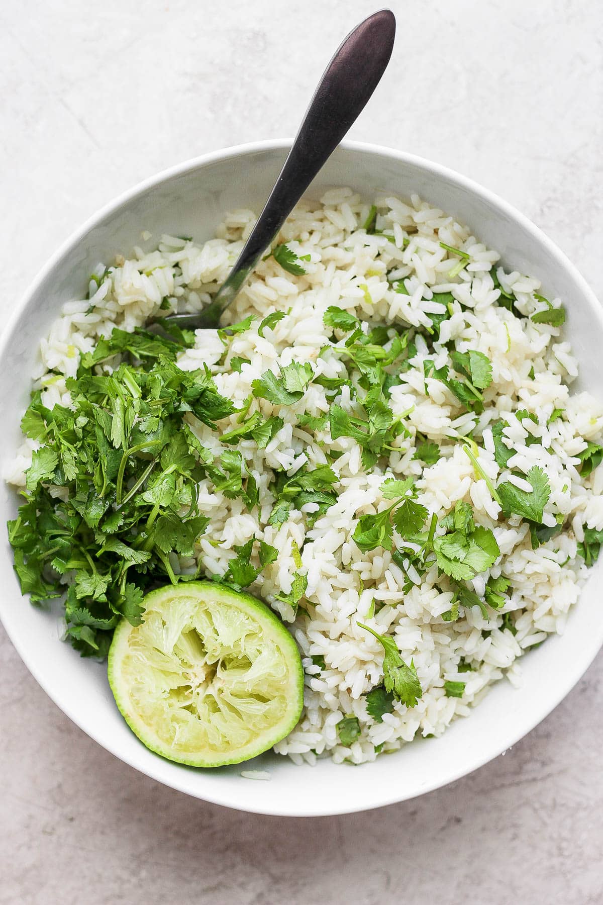 Cilantro lime rice in a white bowl with a spoon.