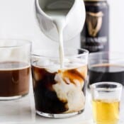 An irish cold brew coffee with cream being added and guinness in the background.