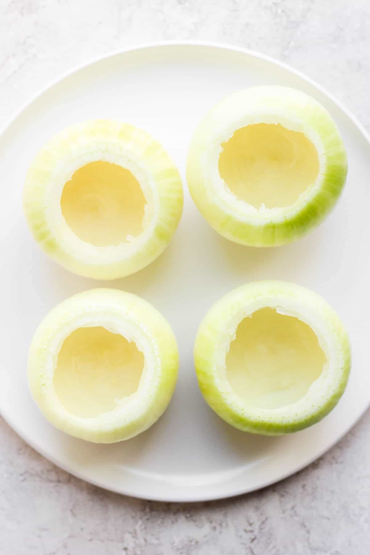 A plate of four hollowed out onions. 