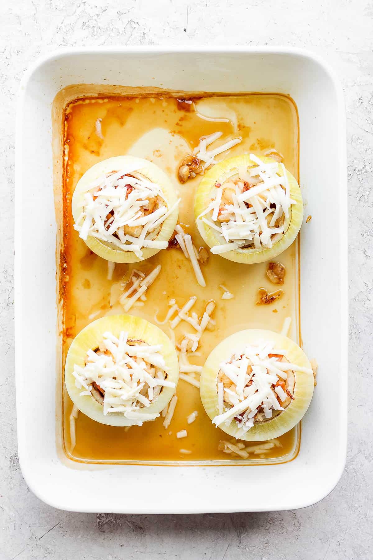 A baking pan with 4 stuffed onions prior to baking. 