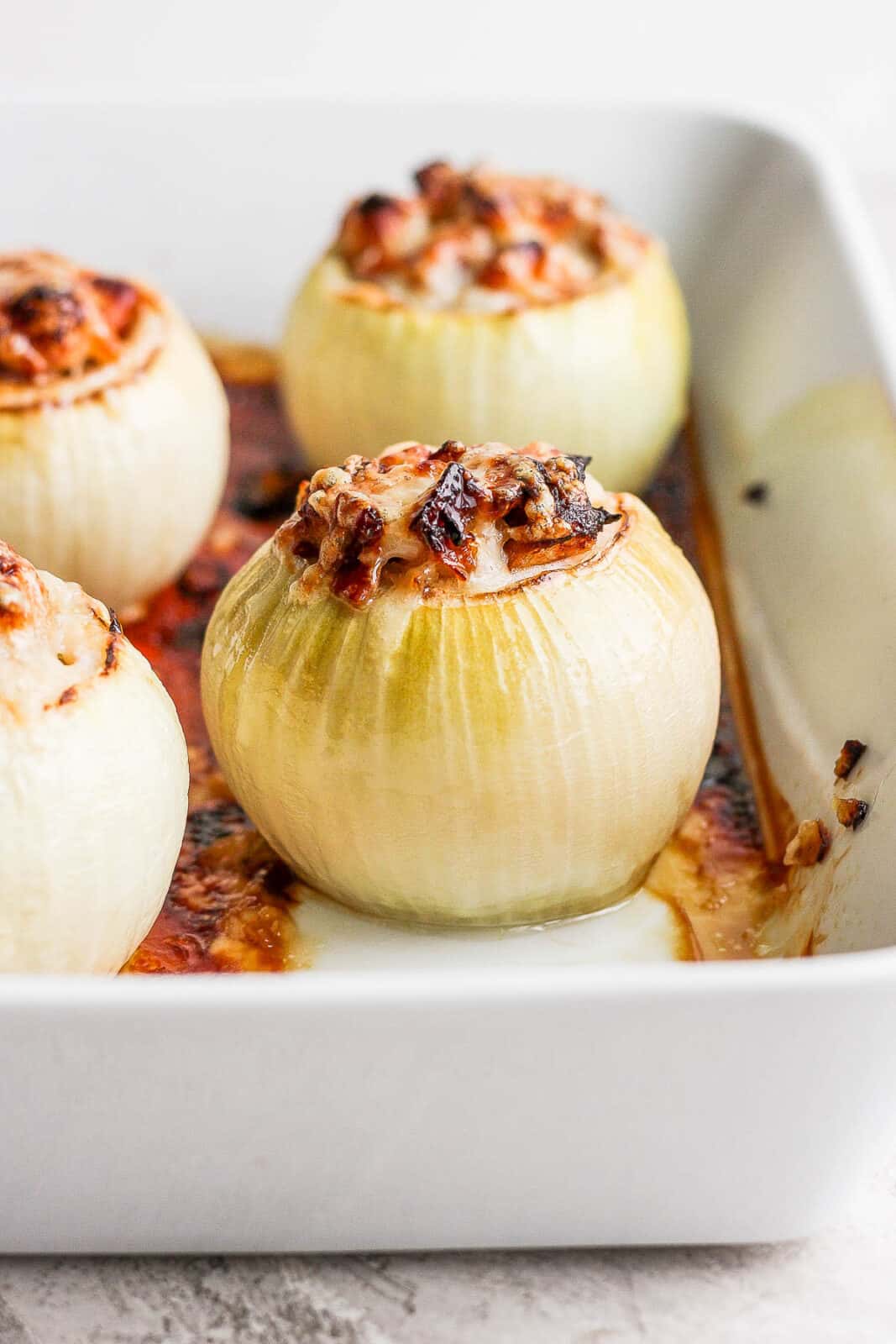A side shot of a pan of four stuffed onions. 