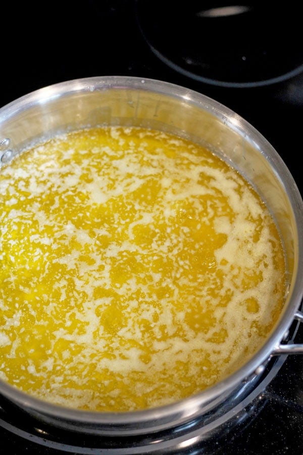 Foam and butter fat gathering on top of simmering butter.