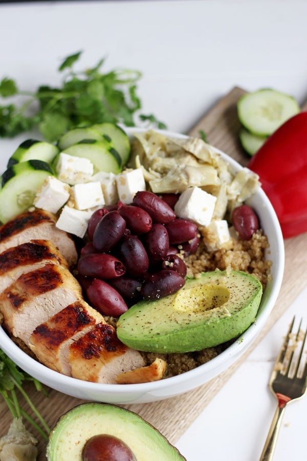 Bowl of quinoa, chicken, feta cheese, olives, cucumber and avocado. 