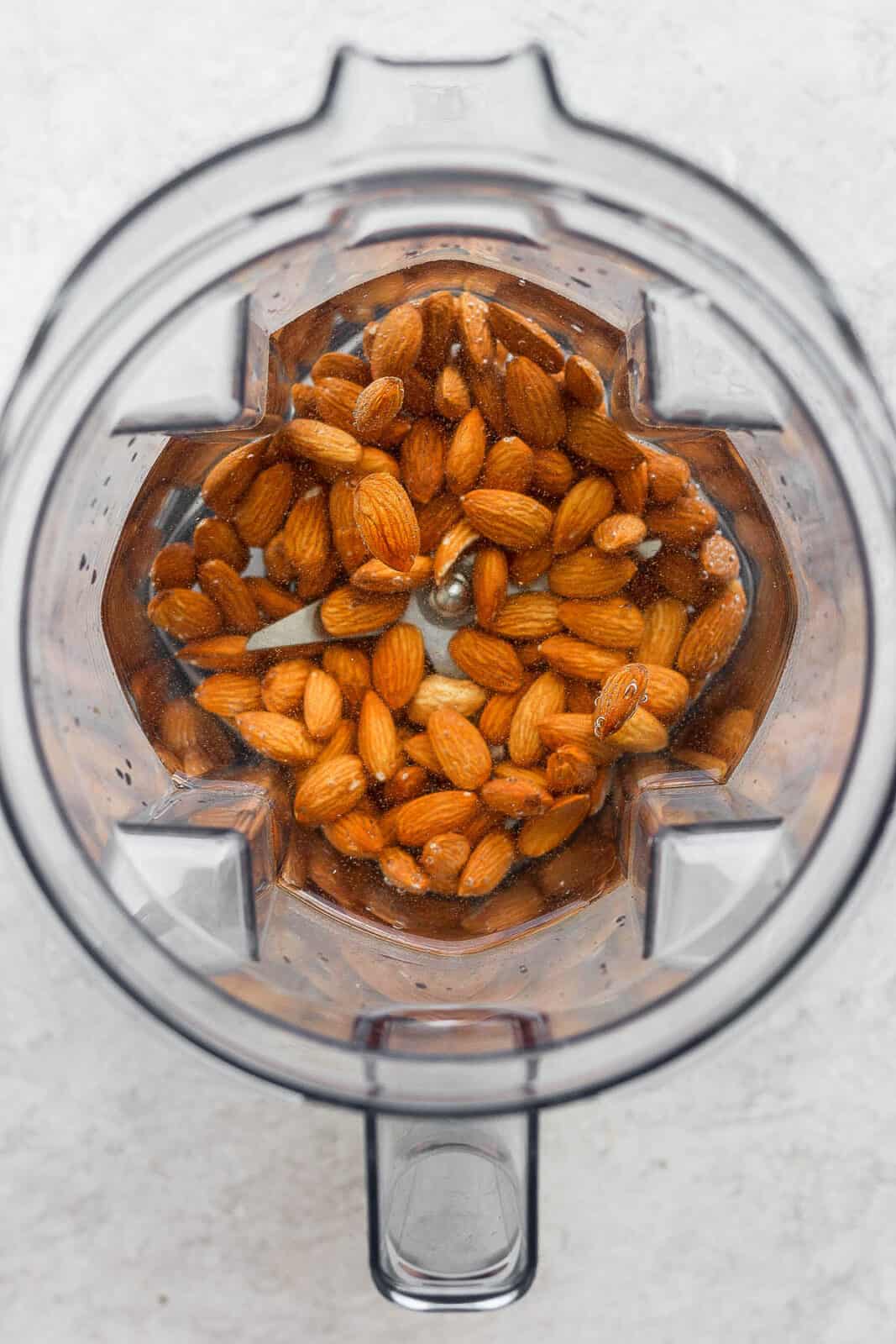 Raw almonds in a blender with water.