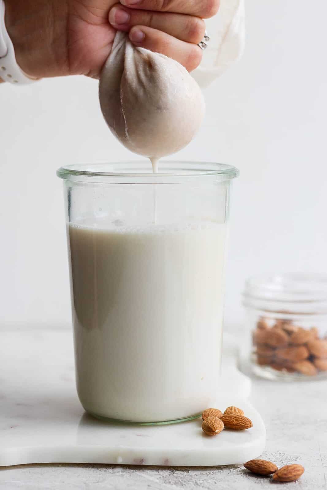 Someone squeezing a cheesecloth as they are making almond milk. 