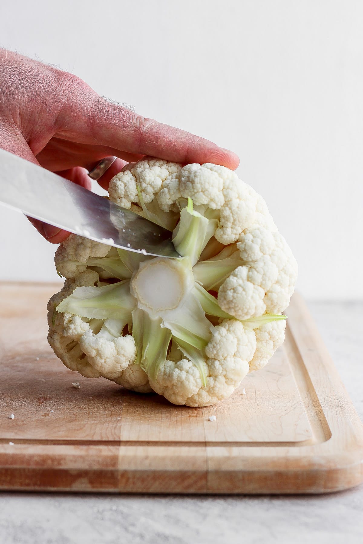 Someone cutting cauliflower into chunks. 