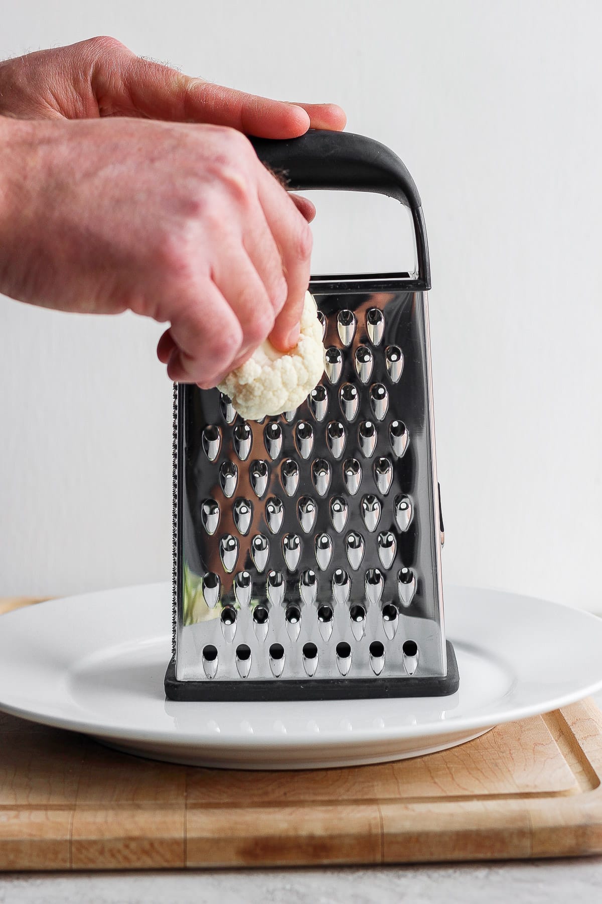 Someone grating cauliflower by hand. 