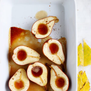 Baked maple cardamom pears in a white baking dish.