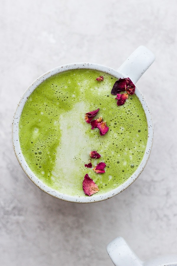 Matcha latte in a mug with some dried rose petals sprinkled on top. 
