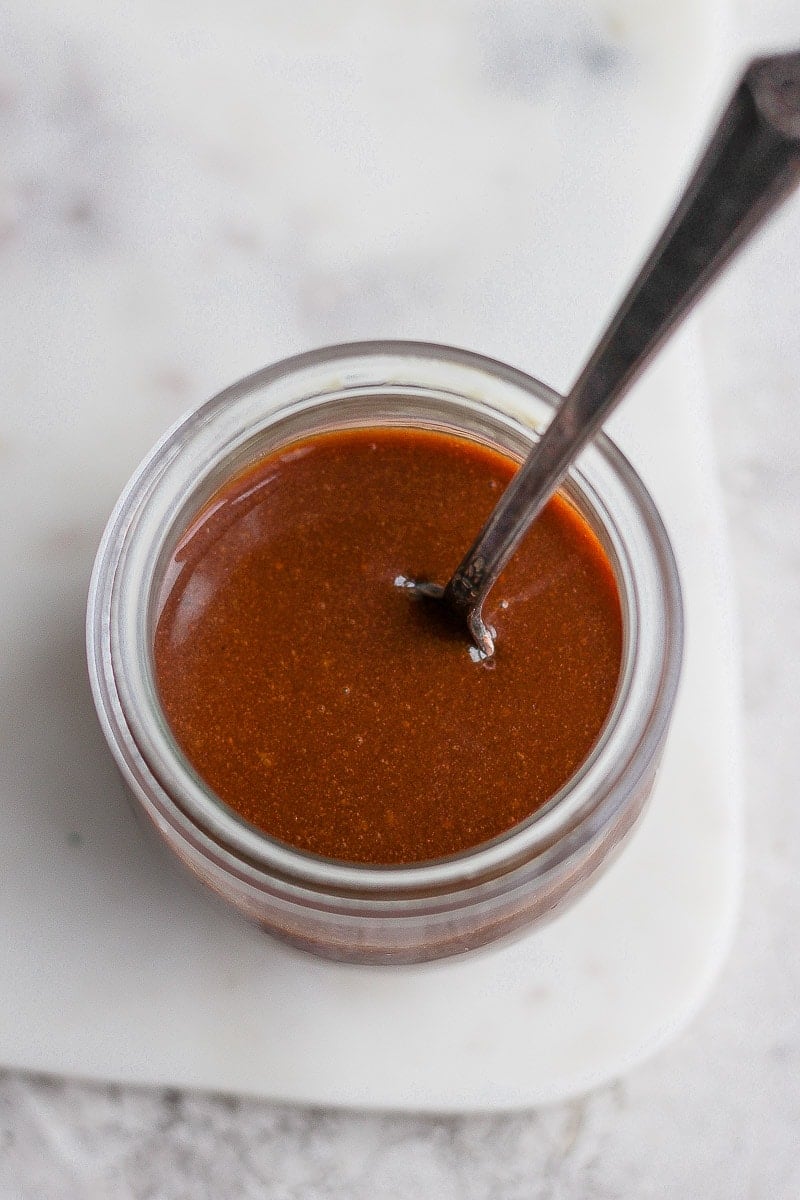 Jar of vegan caramel sauce with spoon sticking out. 