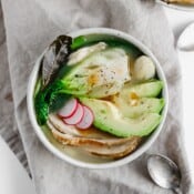 A bowl of asian-inspired leftover turkey soup next to a spoon.