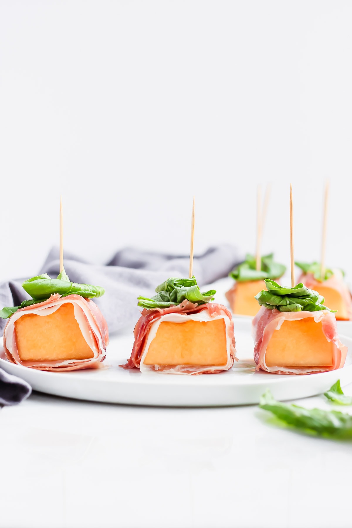 Cantaloupe wrapped with prosciutto and basil with a toothpick holding everything together. 