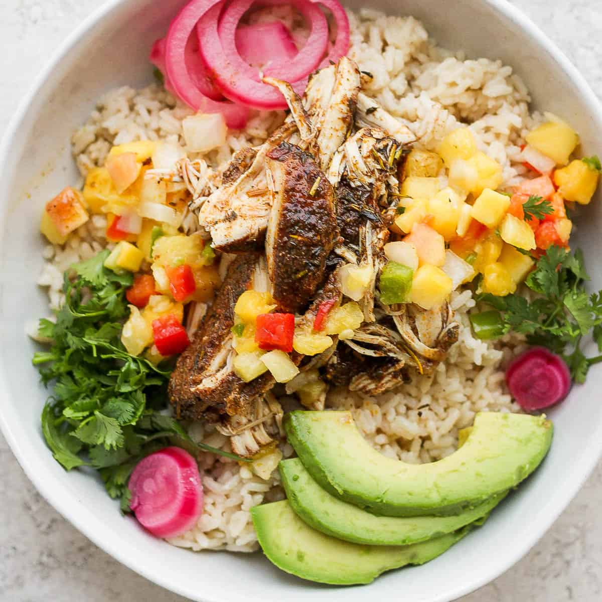 Bowl of crock pot jerk chicken with rice and avocado.