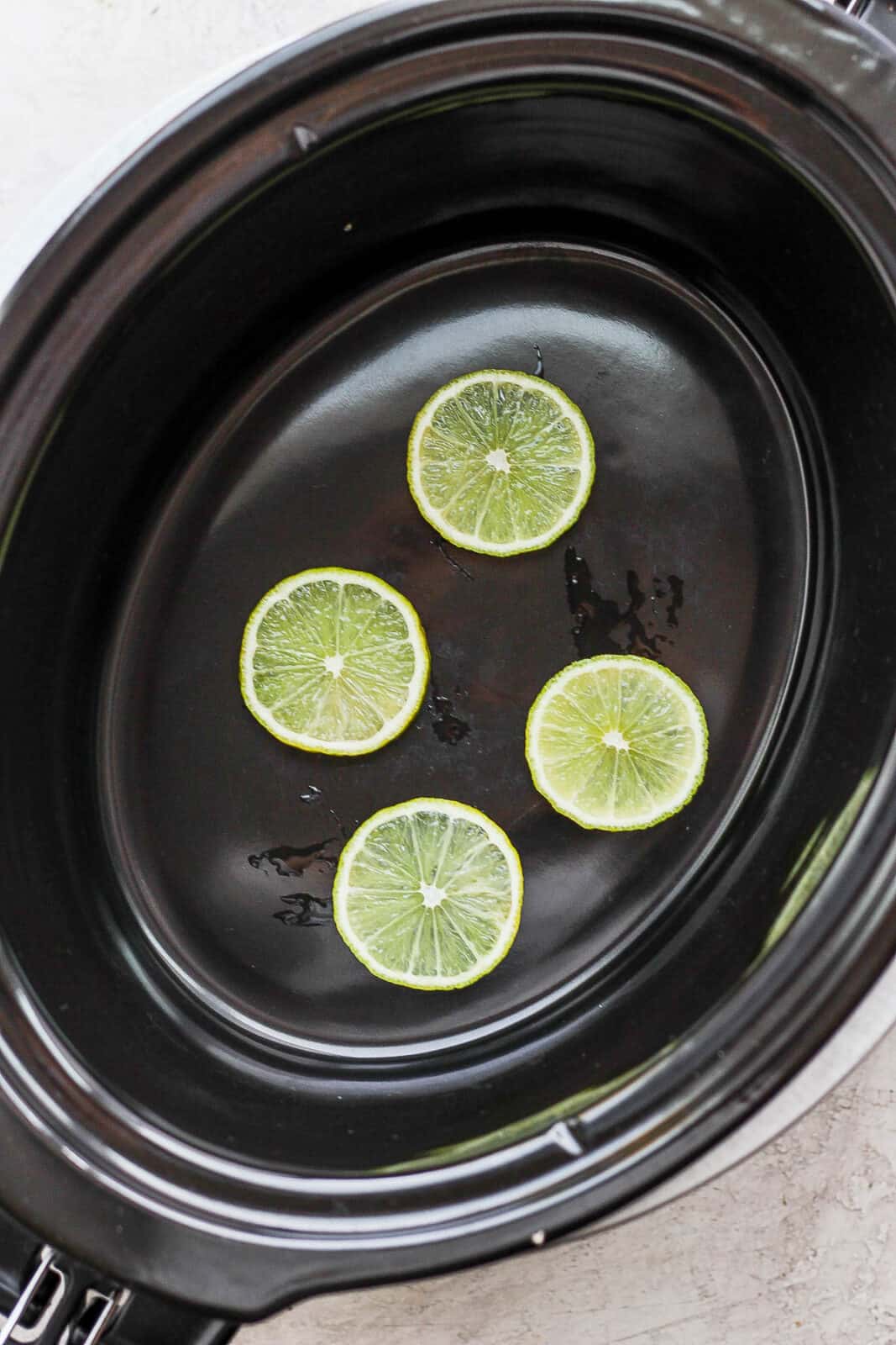 Lime slices in an empty slow cooker. 