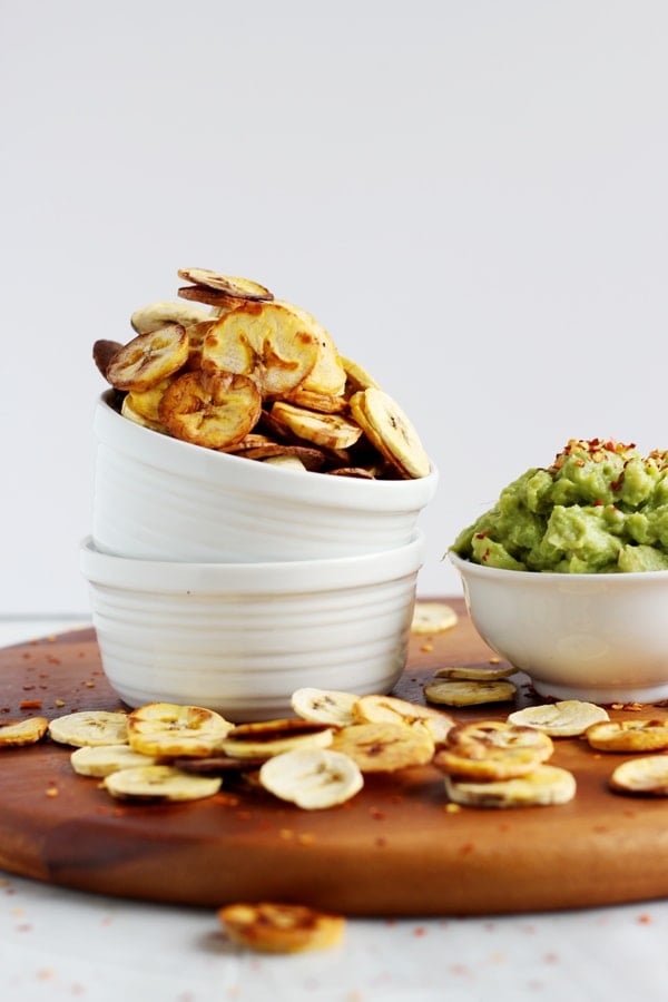 A bowl of plantain chips next to guacamole.