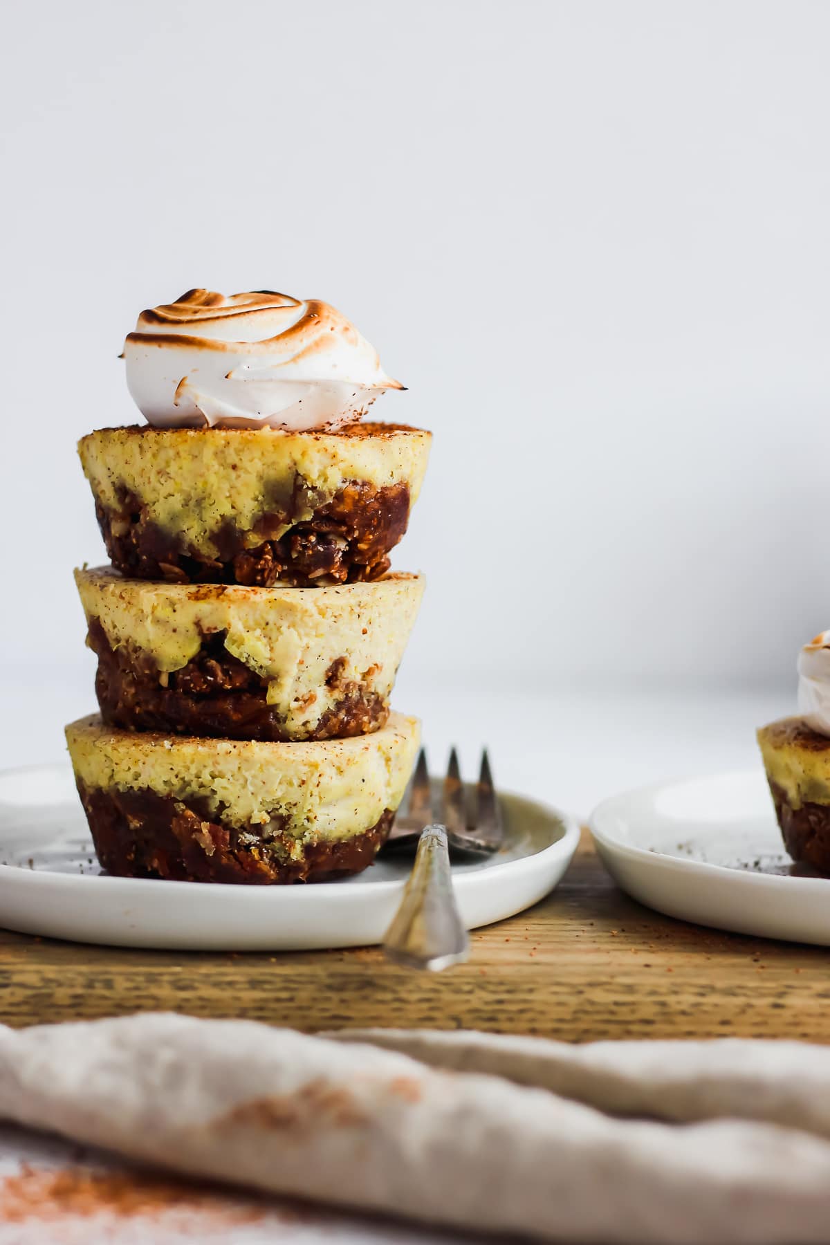 A stack of three egg nog cheesecake bites on a plate with a fork.