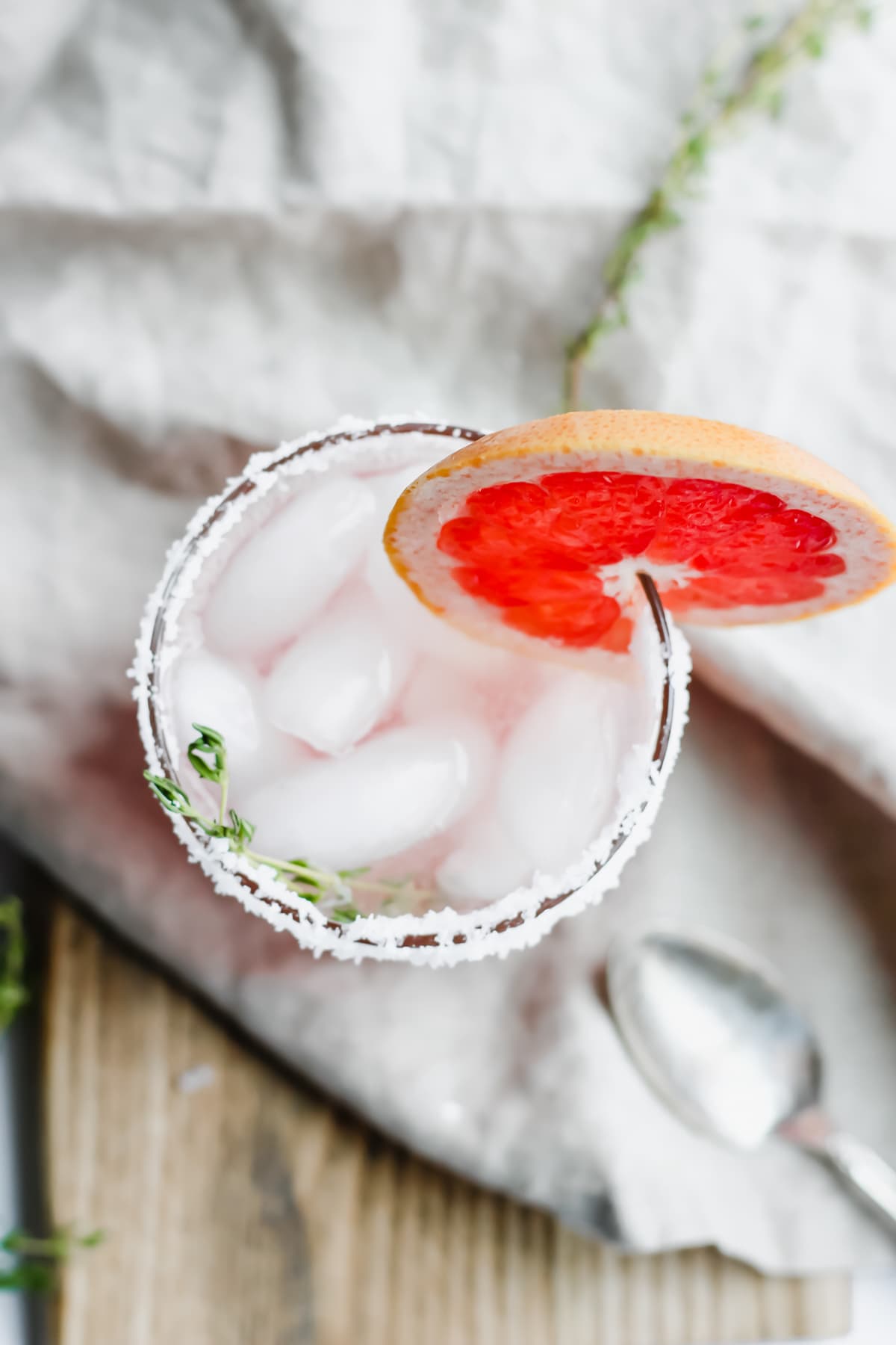 Top shot of a Citrus Paloma Mocktail with Thyme in a glass.