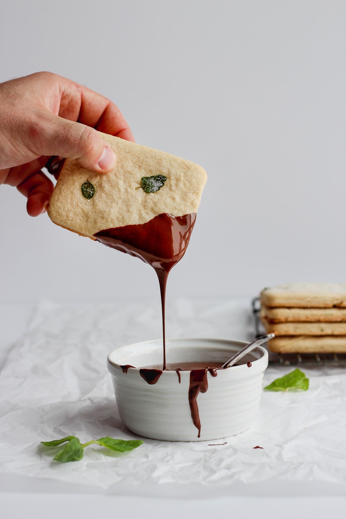 A vegan shortbread cookie being dipped in melted chocolate.